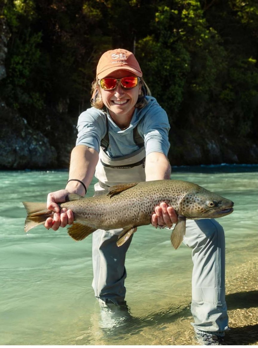 A smiling angler holding a large brown trout