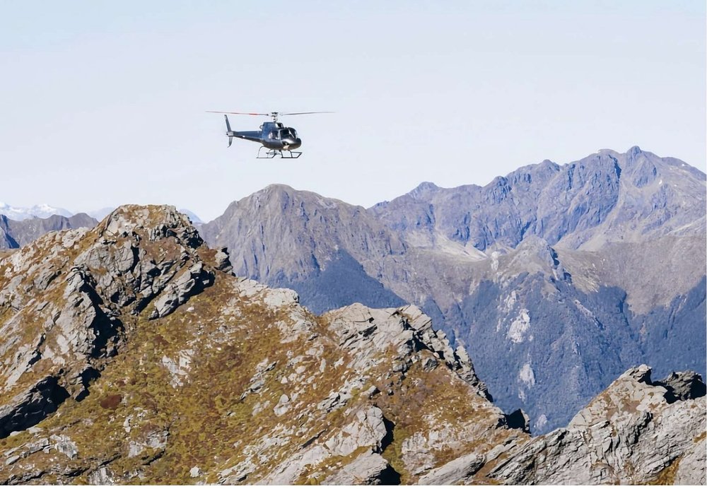 A helicopter flying past rugged Kahurangi peaks