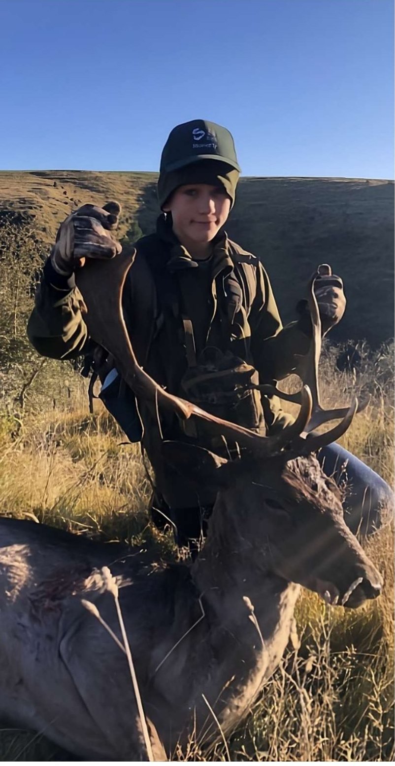 A hunter with a fallow buck at sunrise