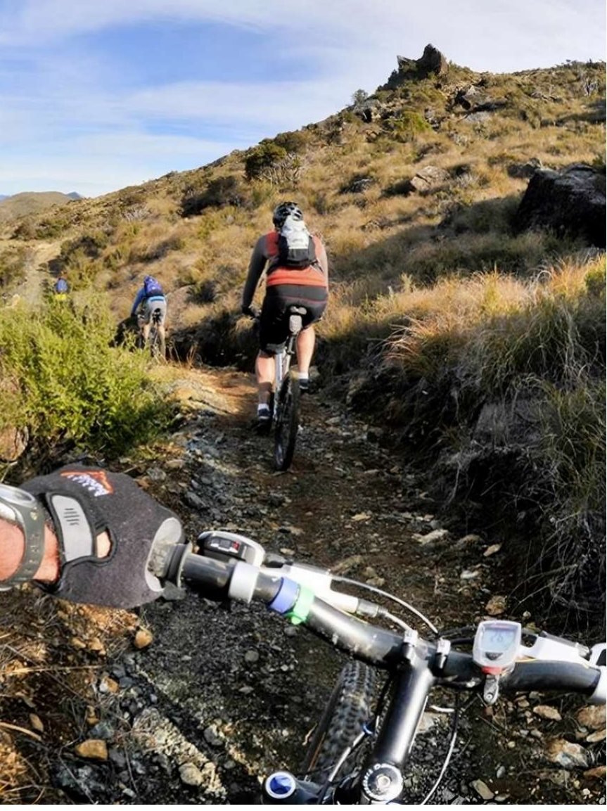 A rider on a narrow backcountry singletrack seen from the handlebars