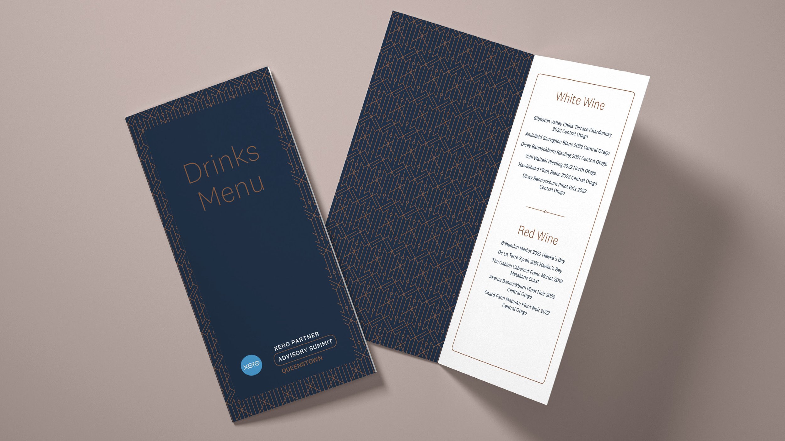 Two drink menus, one closed and one open, with a dark blue and gold geometric design and white backgrounds for the text. The closed menu says 'Drinks Menu' and the open menu lists white and red wines.