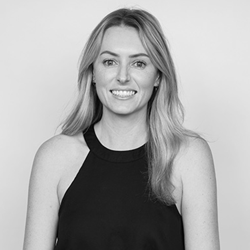 Black and white portrait of a woman with long, wavy hair wearing a sleeveless top, smiling at the camera.