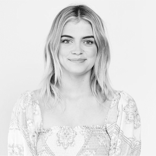 Black and white portrait of a woman with shoulder-length wavy hair, smiling, wearing a patterned top.