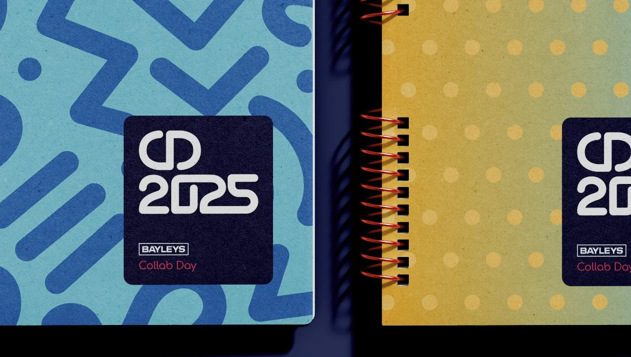 Two spiral notebooks with colorful covers and black labels reading 'CD 2025 BAYLEYS Collab Day.' The left notebook has a blue background with abstract patterns, and the right one has a yellow background with polka dots.