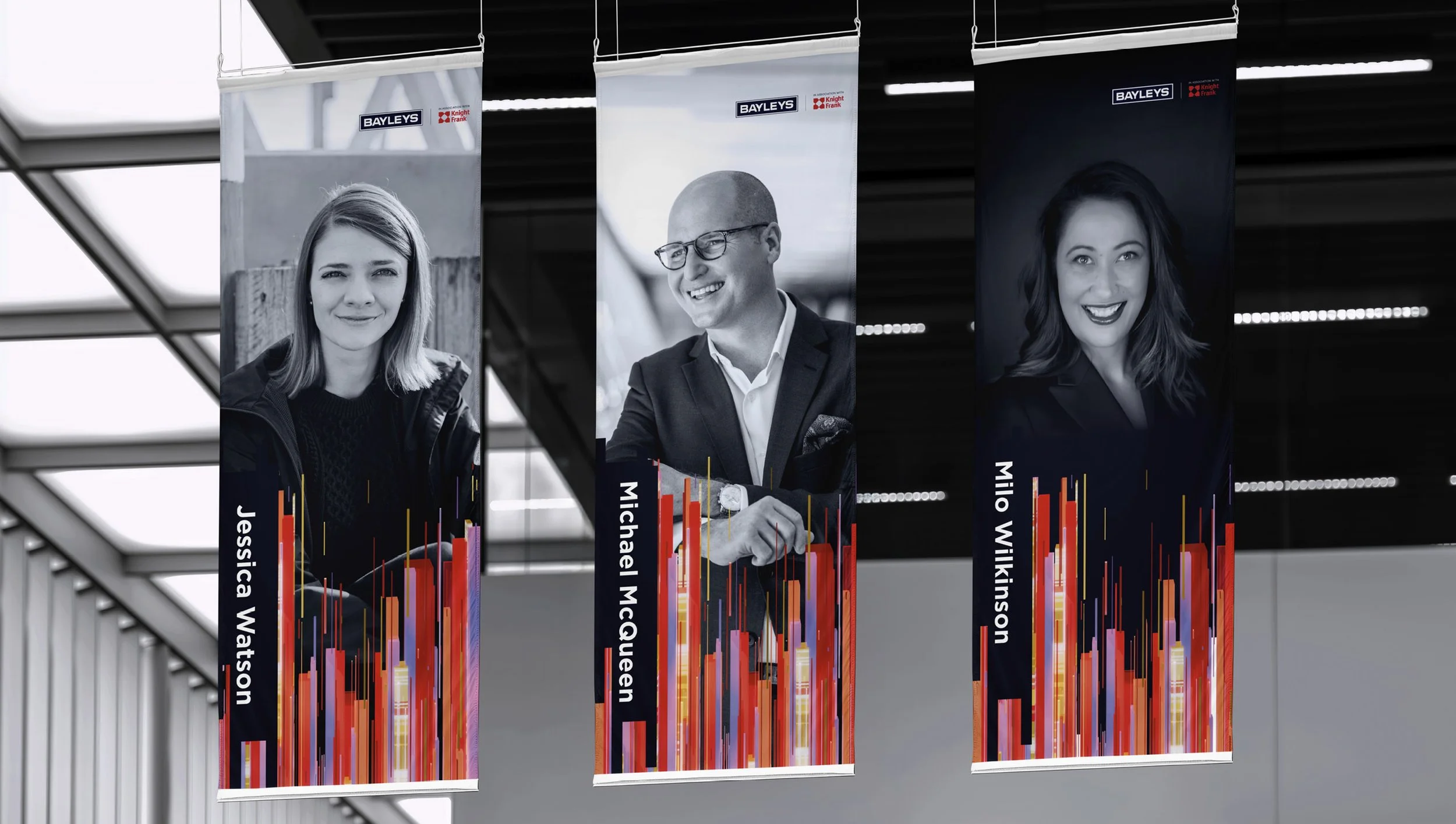 Three banners hanging indoors with black and white portraits of Jessica Watson, Michael McQueen, and Milo Vilkinson, each with colorful graphic designs and their names.