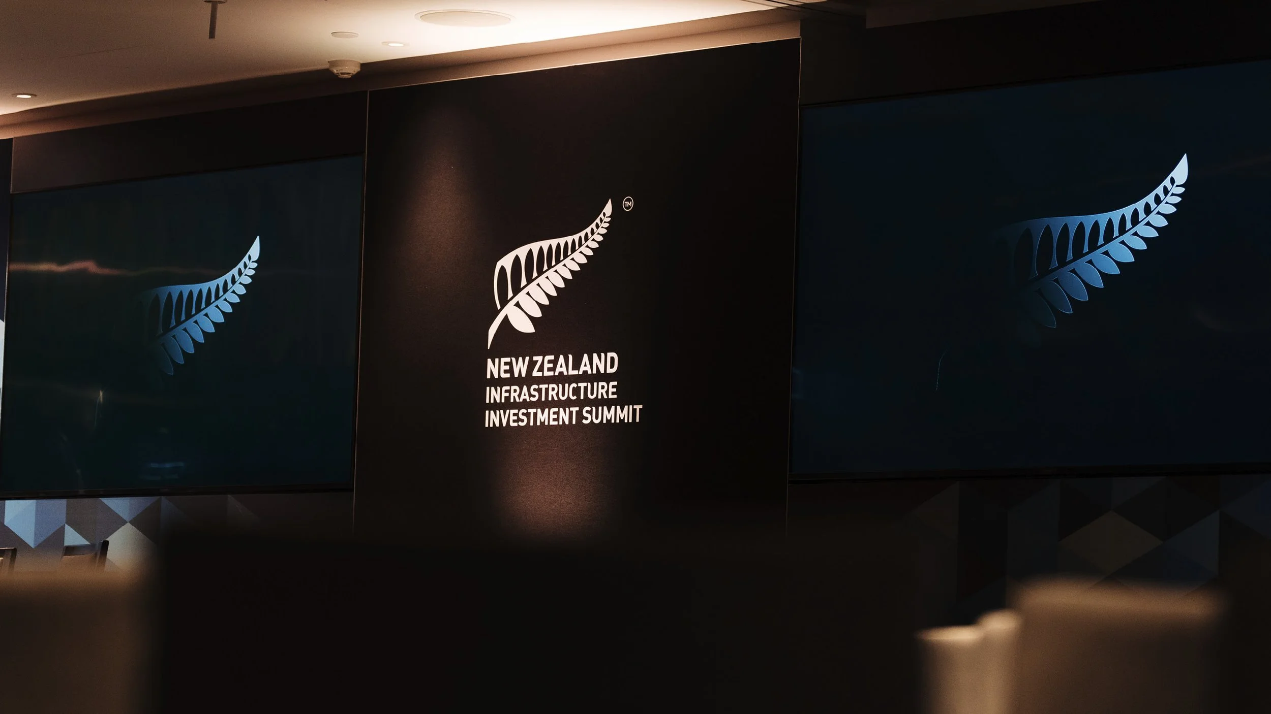 Sign for the New Zealand Infrastructure Investment Summit with the New Zealand silver fern logo on black background.