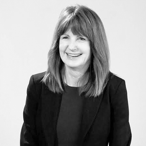 Black and white photo of a woman with shoulder-length hair, smiling, wearing a blazer.