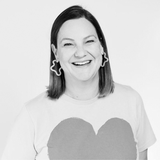 Black and white portrait of a smiling woman with shoulder-length hair wearing large star-shaped earrings and a T-shirt with a heart design.
