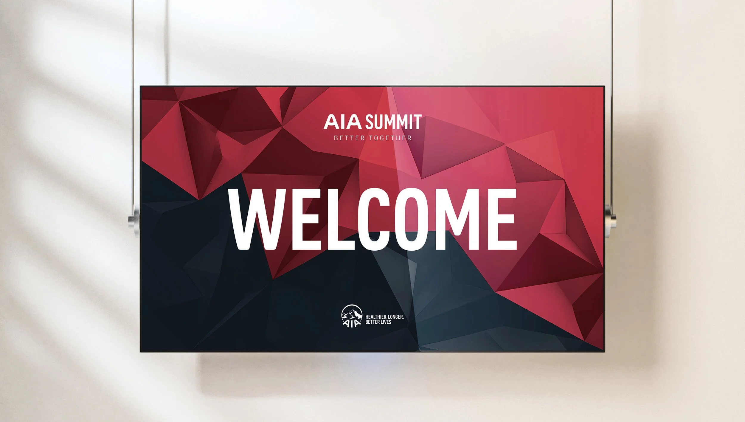 Digital screen displaying a welcome message for the AIA Summit with a geometric red and black background, and the AIA logo at the bottom.