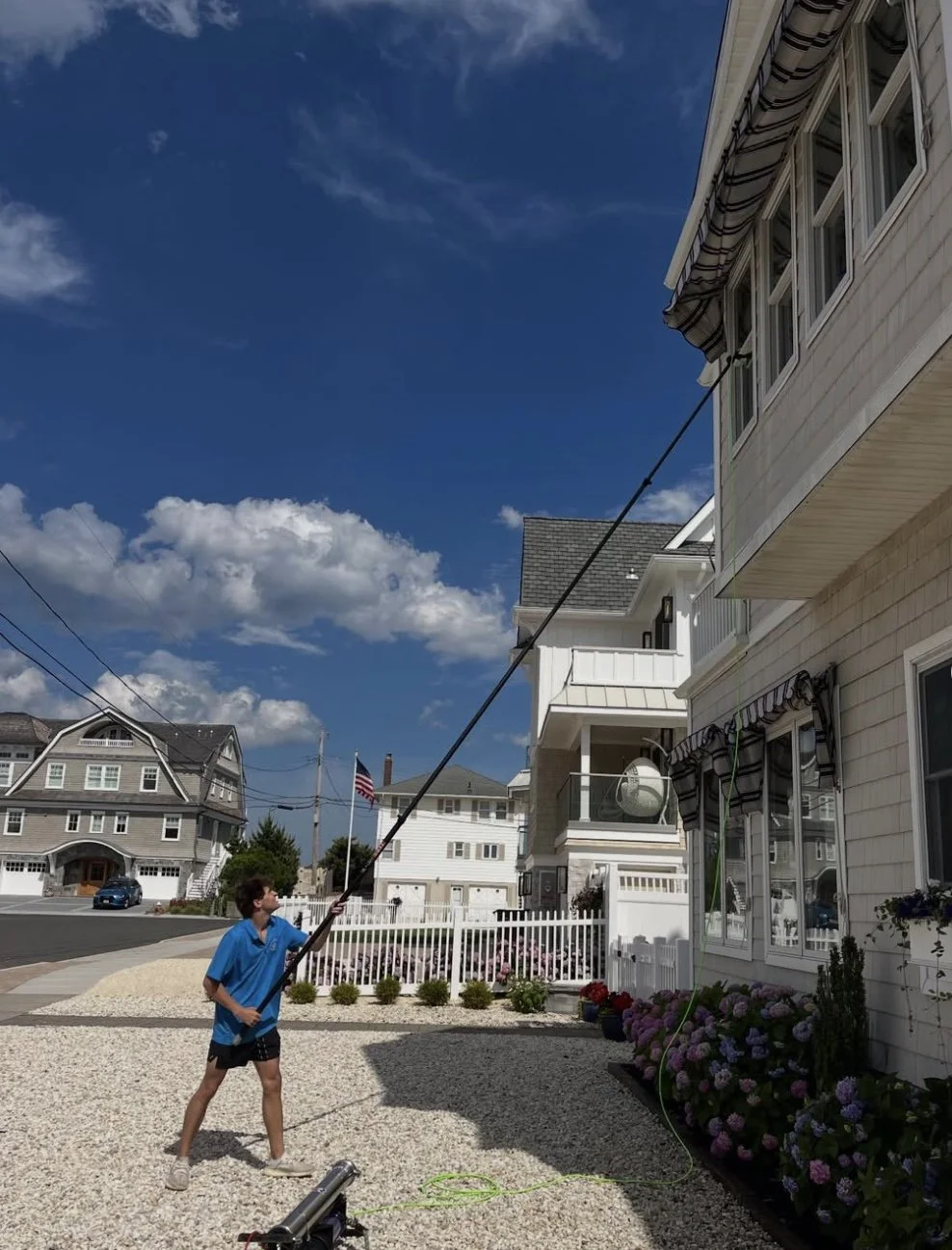 Hooks Property Services technician cleaning second-story windows with a water-fed pole