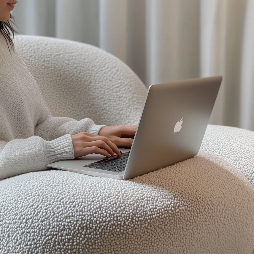 Person using a laptop for a virtual therapy session in a comfortable home setting.