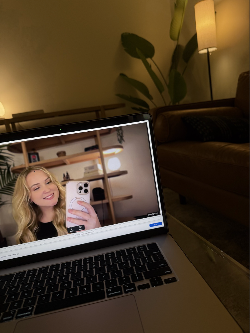Laptop displaying a therapist smiling during a virtual therapy session in a home setting.