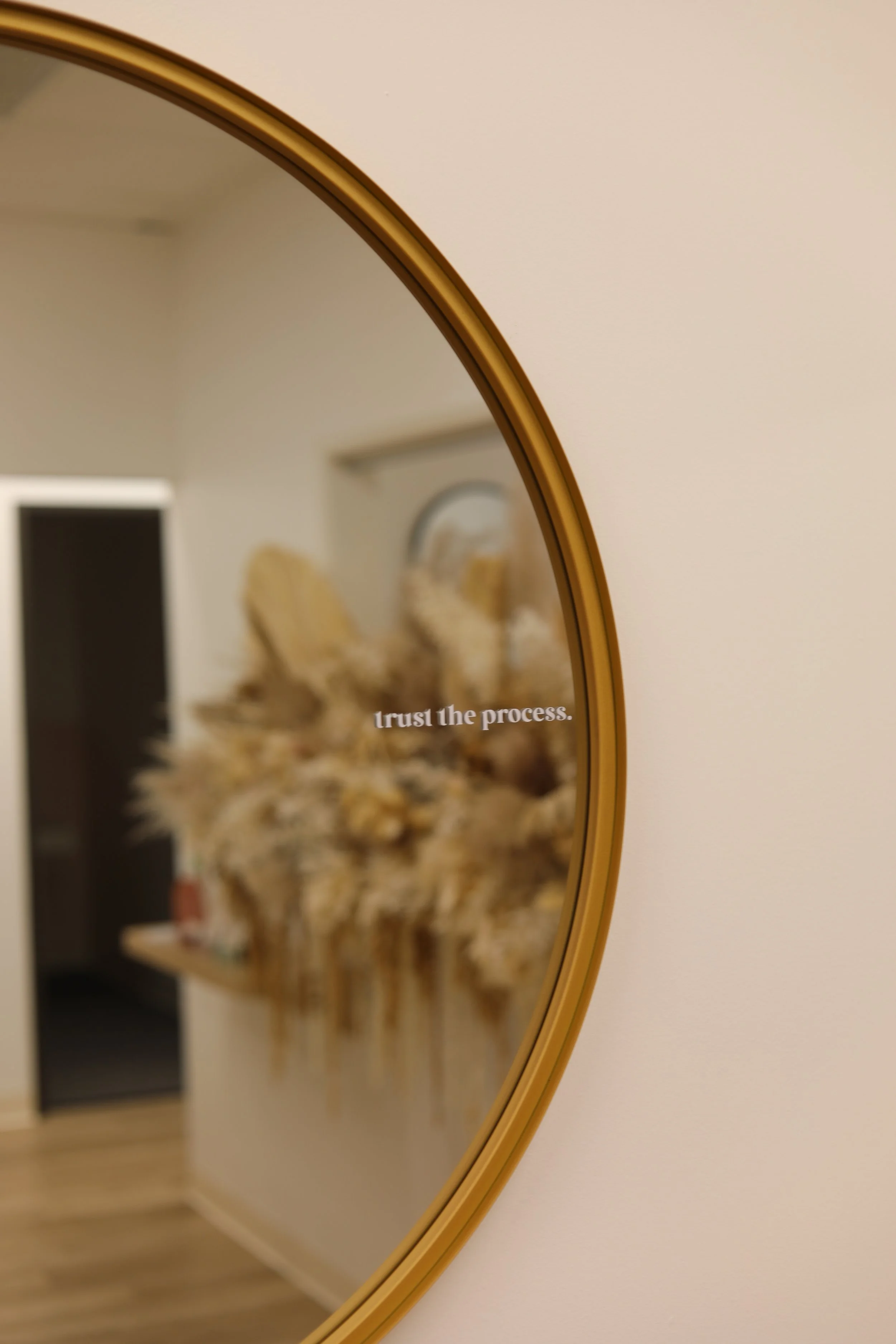 Warm therapy office space in Irvine with gold mirror displaying the phrase “trust the process.”