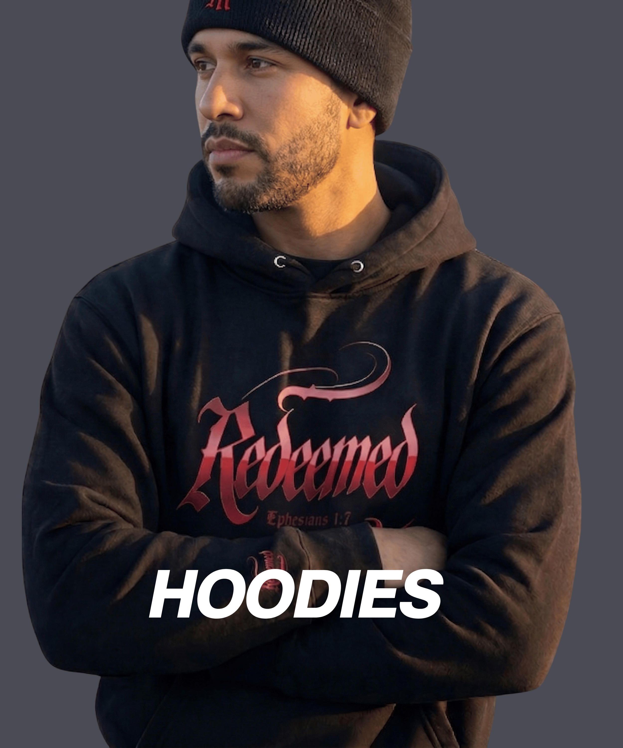 A man wearing a black hoodie with red text and a black beanie, standing with arms crossed against a plain background.