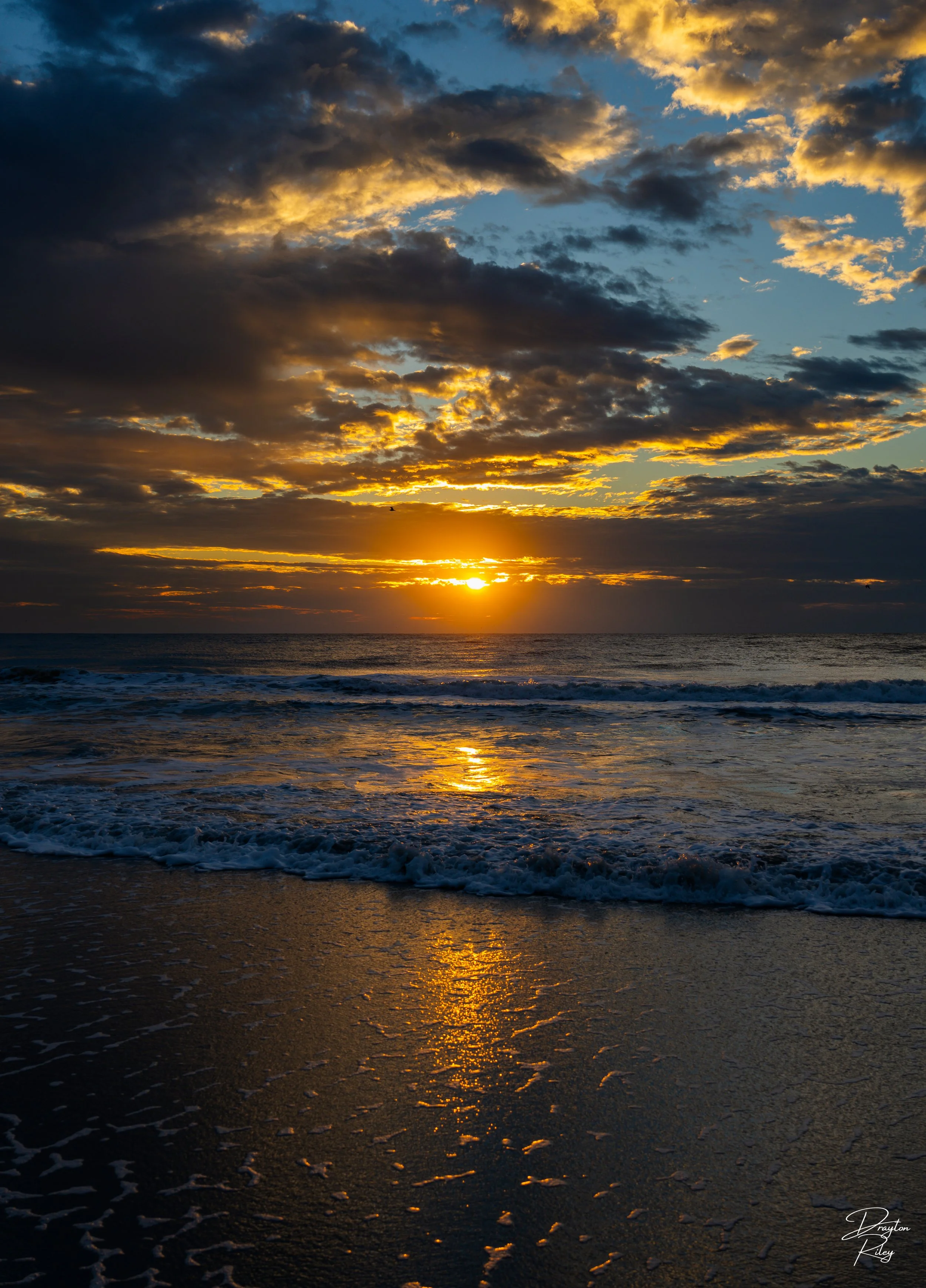 This captivating photograph showcases the serene beauty of a beach at sunset, where the golden hues of the setting sun gently kiss the rippling waves and the reflection dances across the wet sand. 
~Murrels Inlet, South Carolina