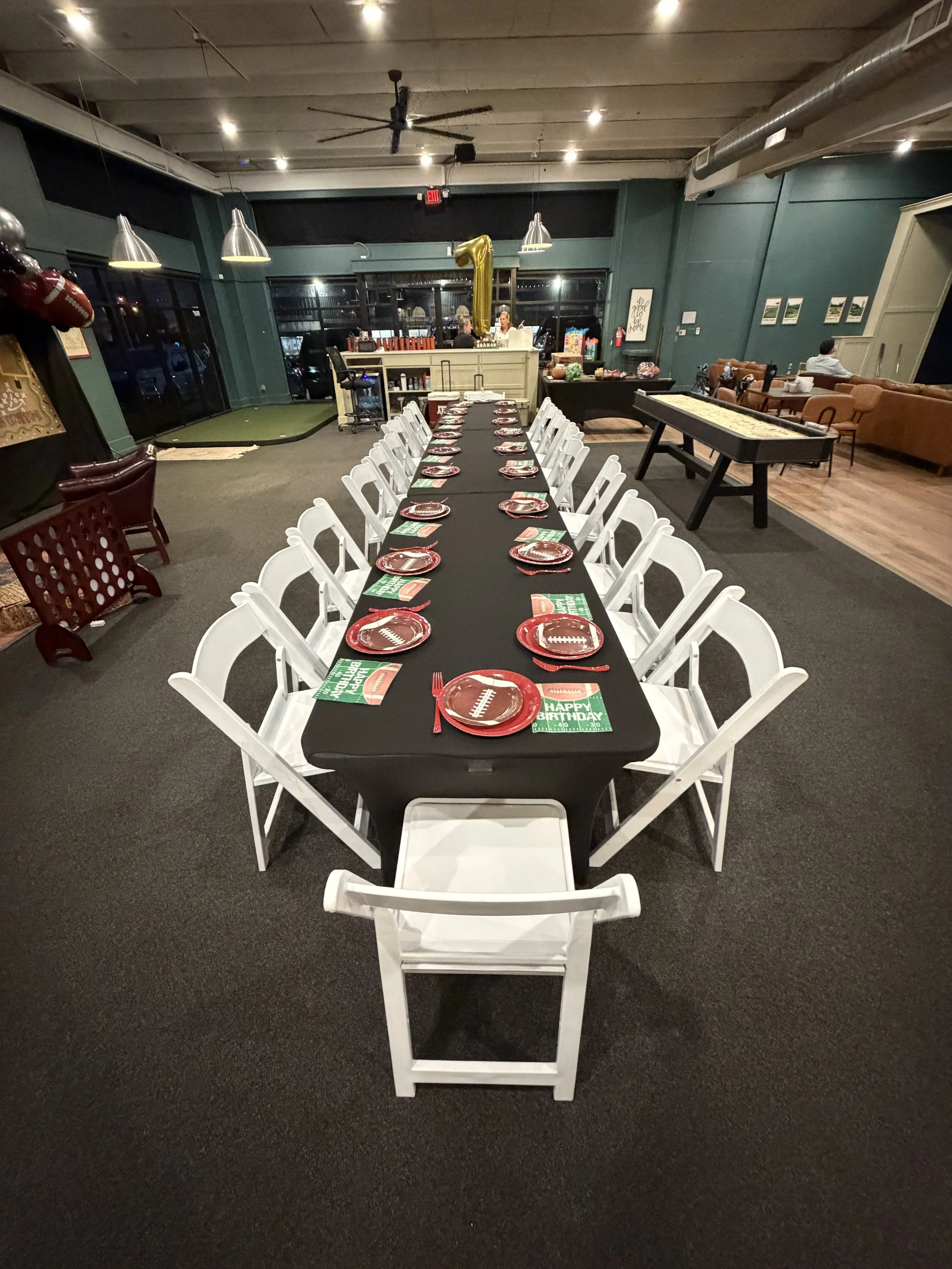 Group of friends celebrating with confetti, holding drinks, and smiling at a party with colorful banners in the background.