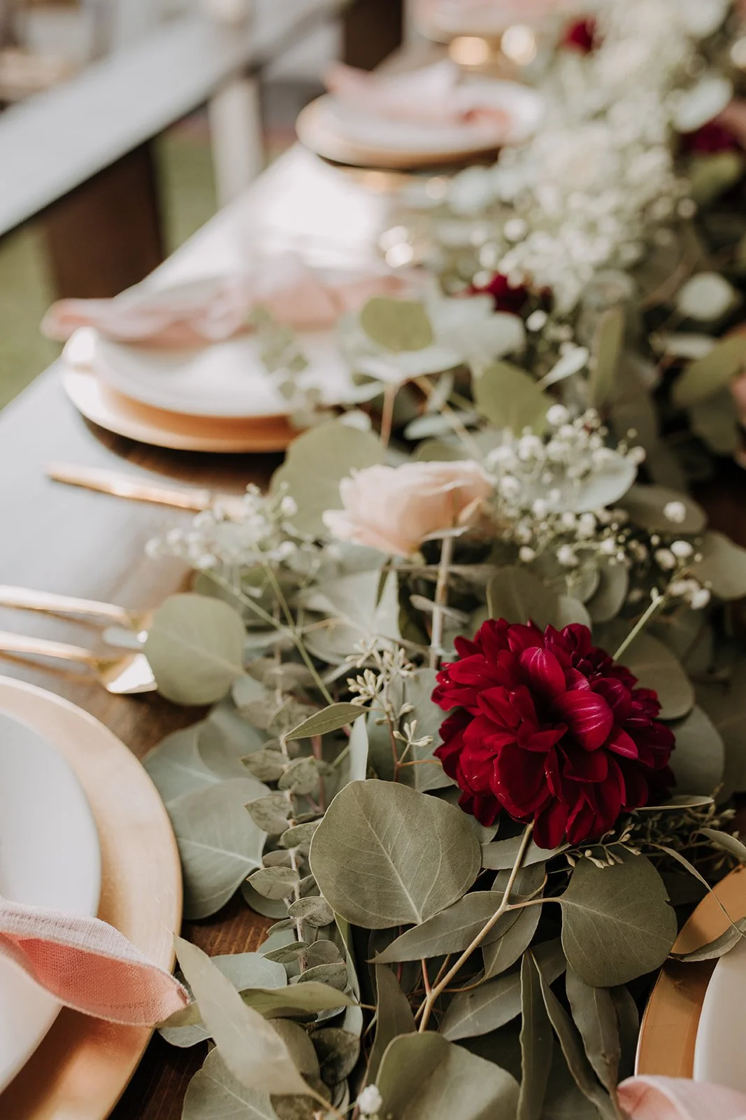 Elegant table setting with roses, eucalyptus, and floral decorations for a special occasion.