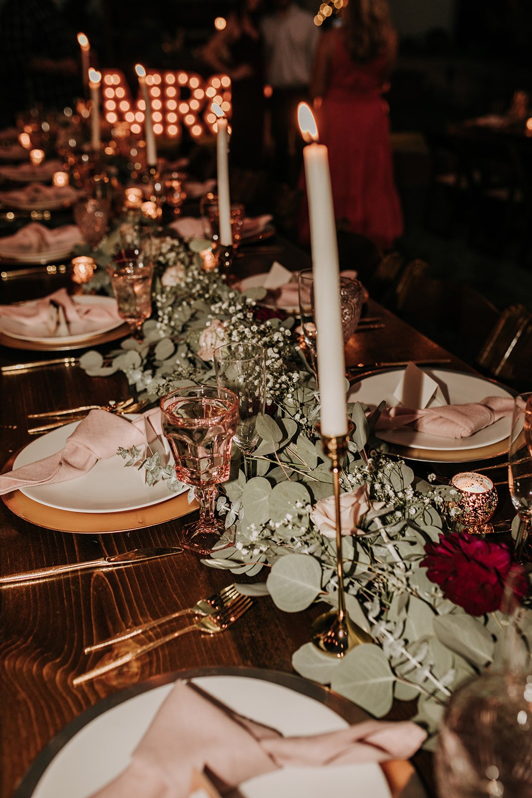 Elegant dinner table decorated with candles, flowers, and glassware for a celebration or event.