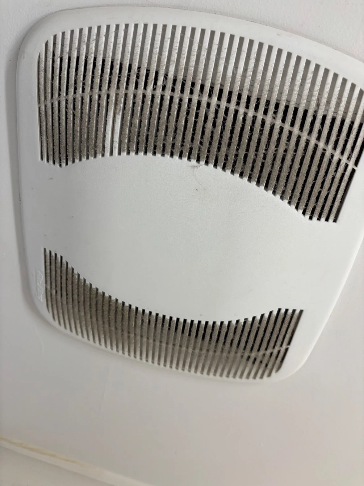 Bathroom exhaust fan grille covered in dust, before cleaning