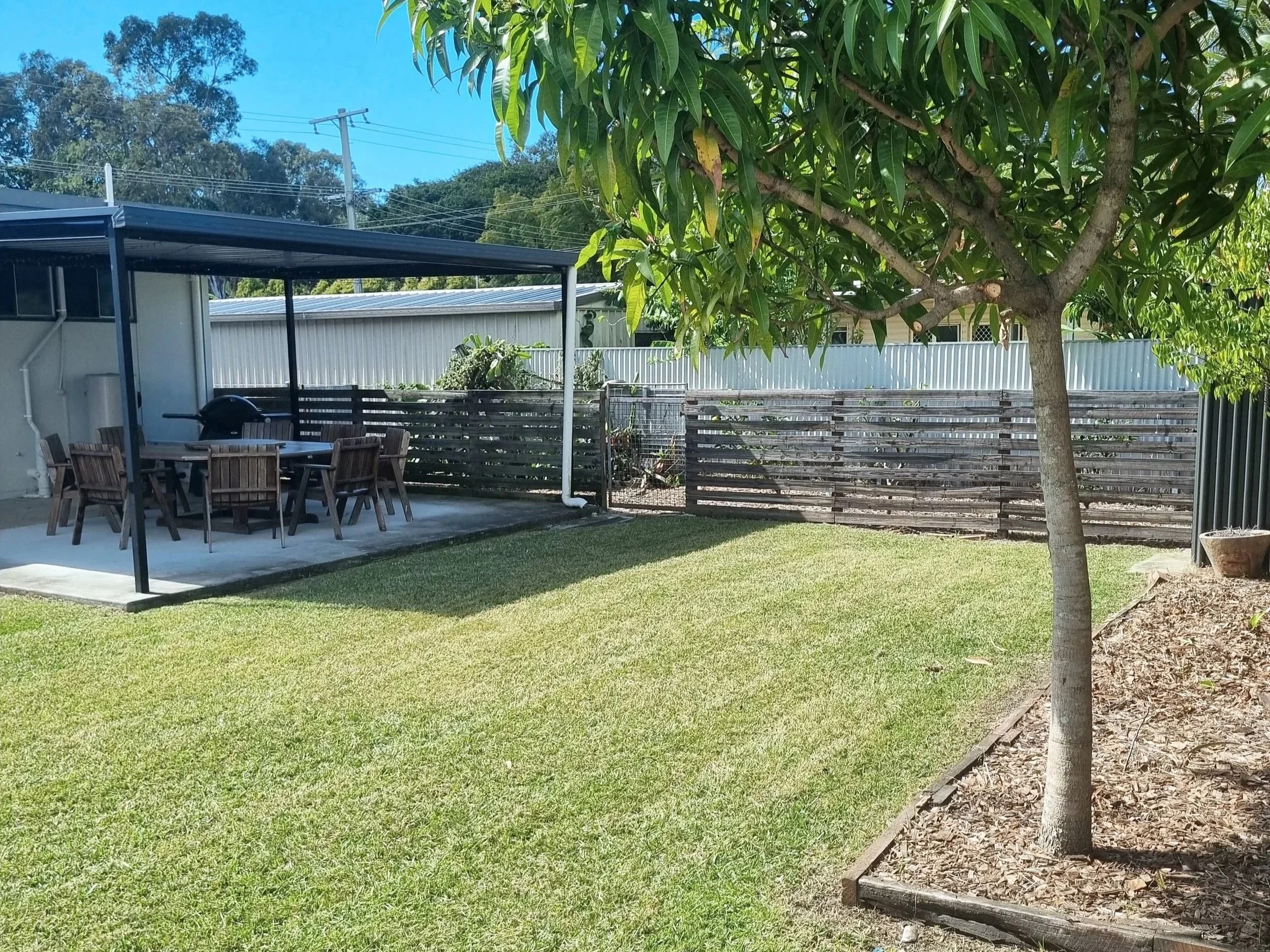 Neat backyard with freshly mowed lawn and tidy garden in North Lakes.
