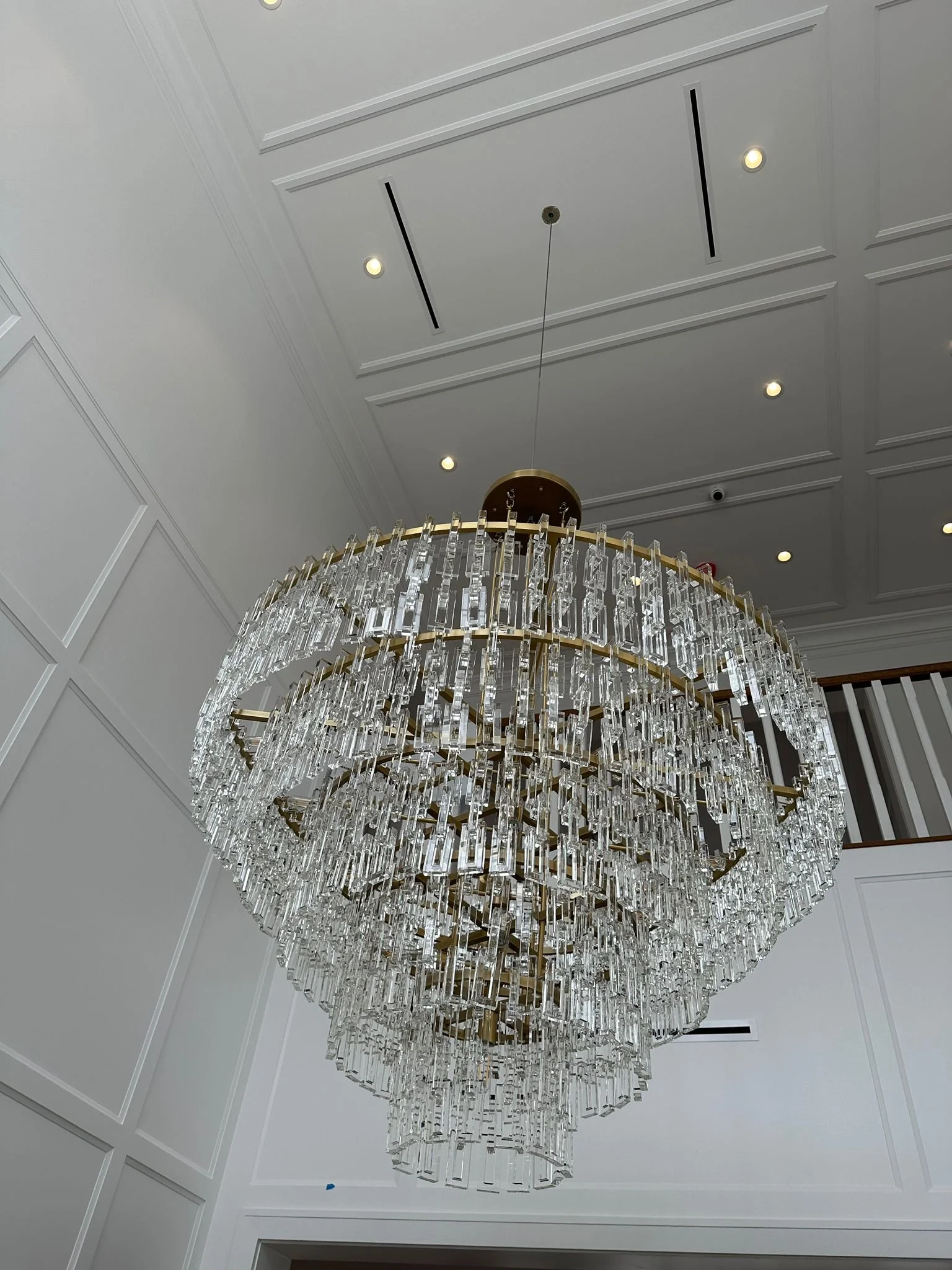A large, ornate crystal chandelier hanging from a ceiling with recessed lighting.
