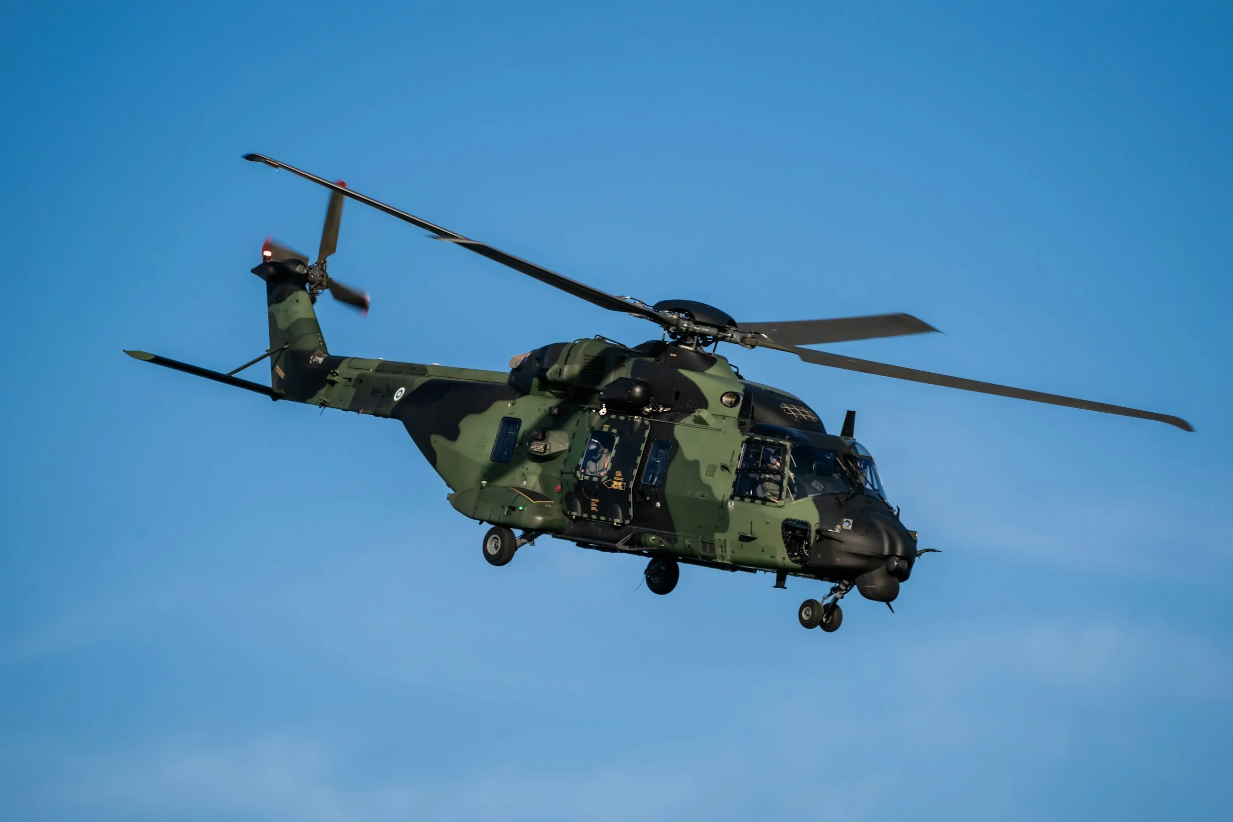 A military camouflage helicopter flying in the sky.