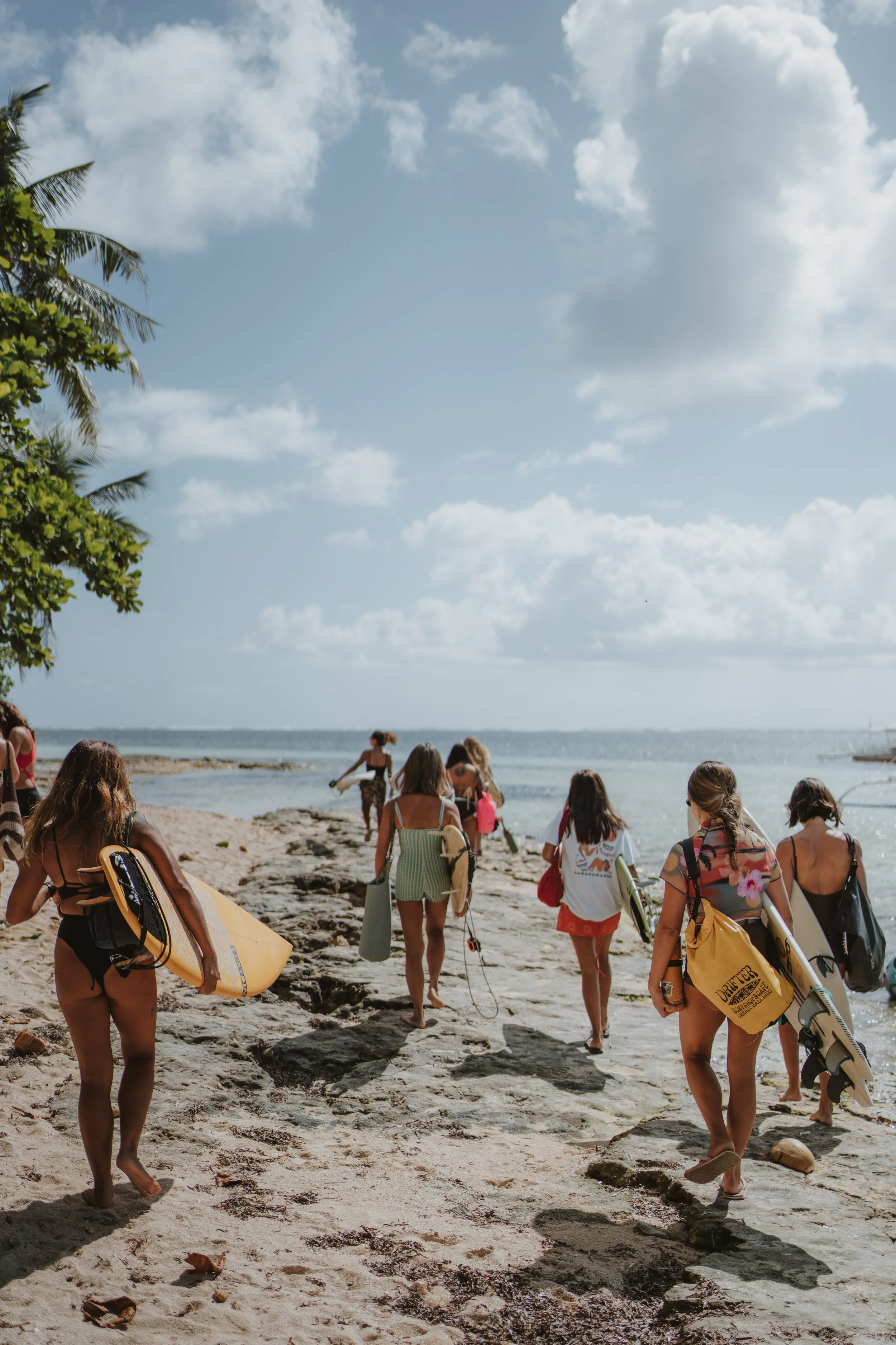 Women surfers walking with shortboards on a beach in Siargao