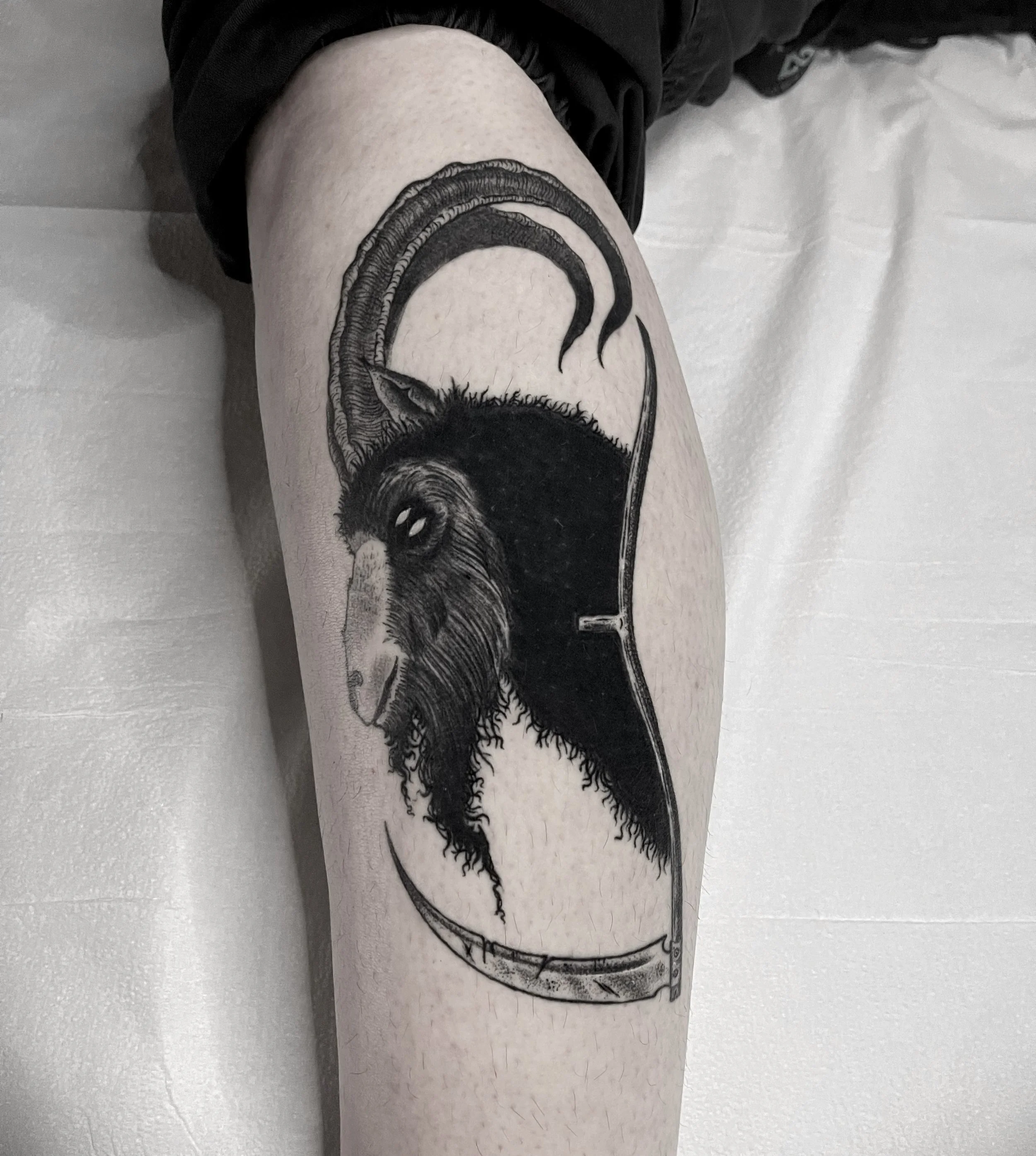 black work dark art illustrated tattoo of a goat and scythe on leg