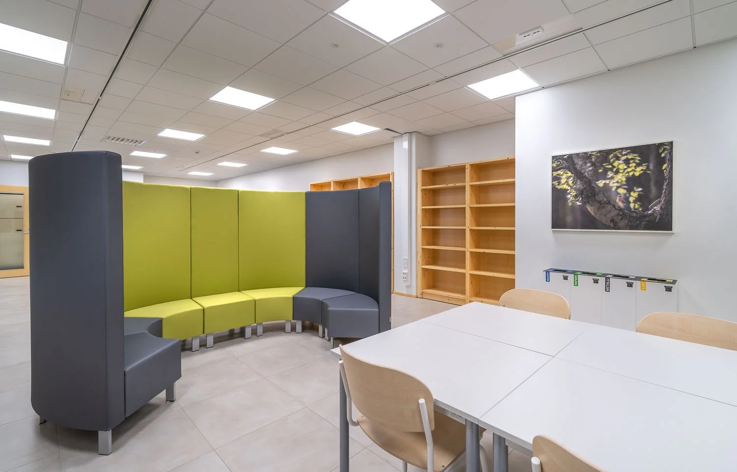 Empty office or conference room with curved seating, wooden shelving, and a table with chairs.
