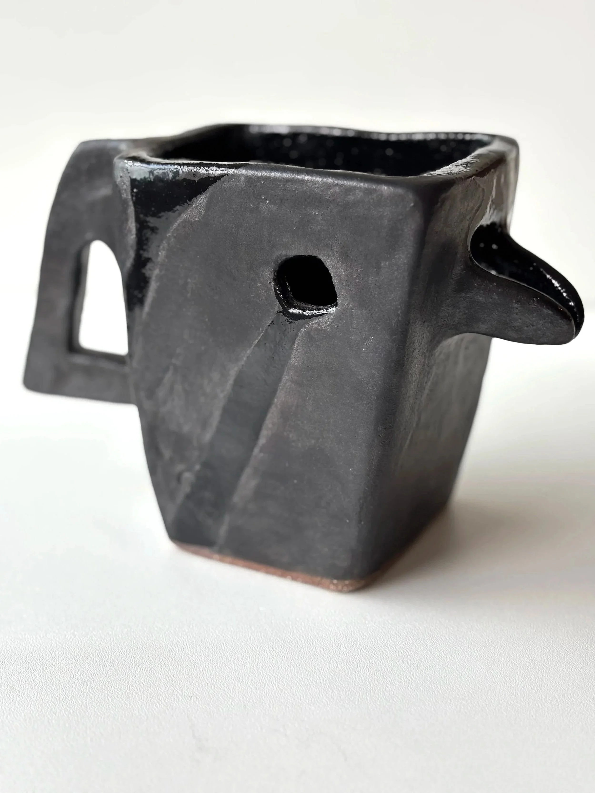 Tasse en céramique noire avec une forme stylisée d'une tête de taureau