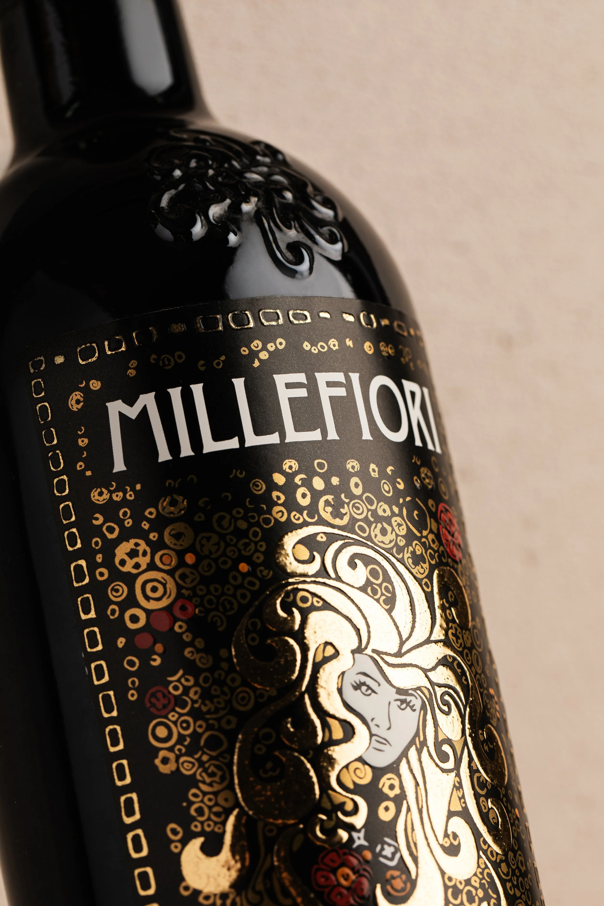 Close-up of a black beer bottle with a decorative label featuring a gold and black design, a woman's face, and the text 'Millflower'.