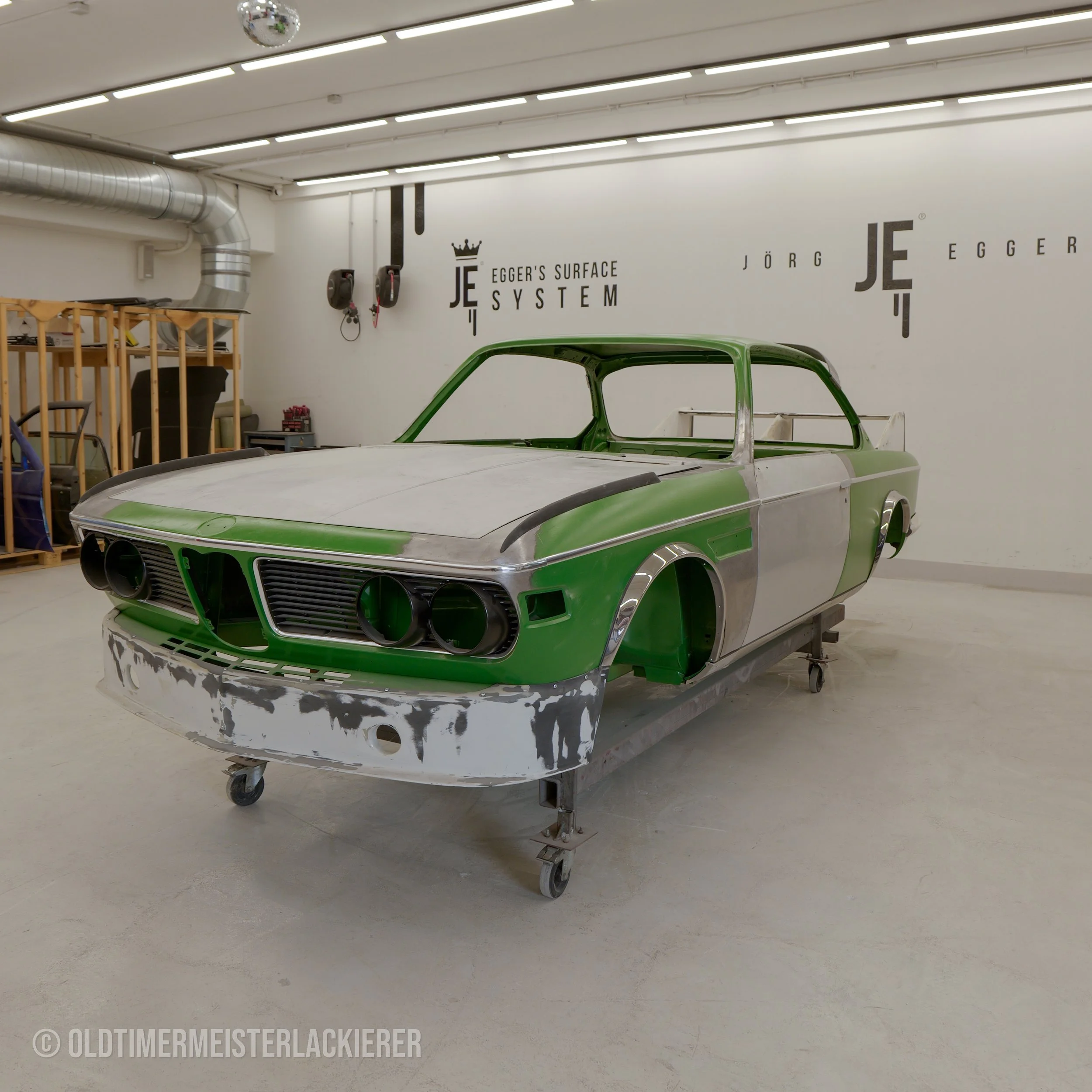 Zu sehen ist die Rohkarosse einer BMW CSL „Batmobile“, die mit allen formgebenden Teilen montiert angeliefert wurde. Nur so können Spaltmaße exakt kontrolliert und die Grundlage für eine hochwertige Lackierung geschaffen werden.