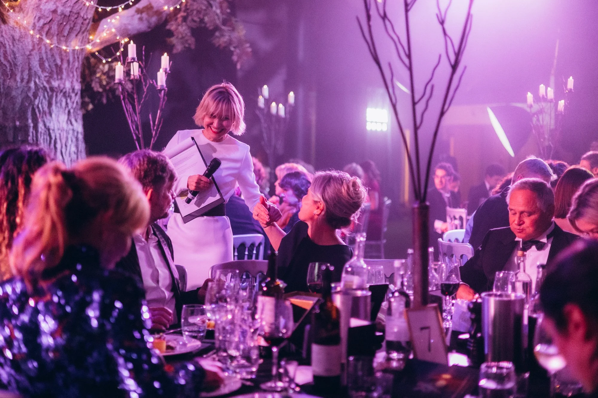 Gala dinner tables under purple lighting during a corporate event