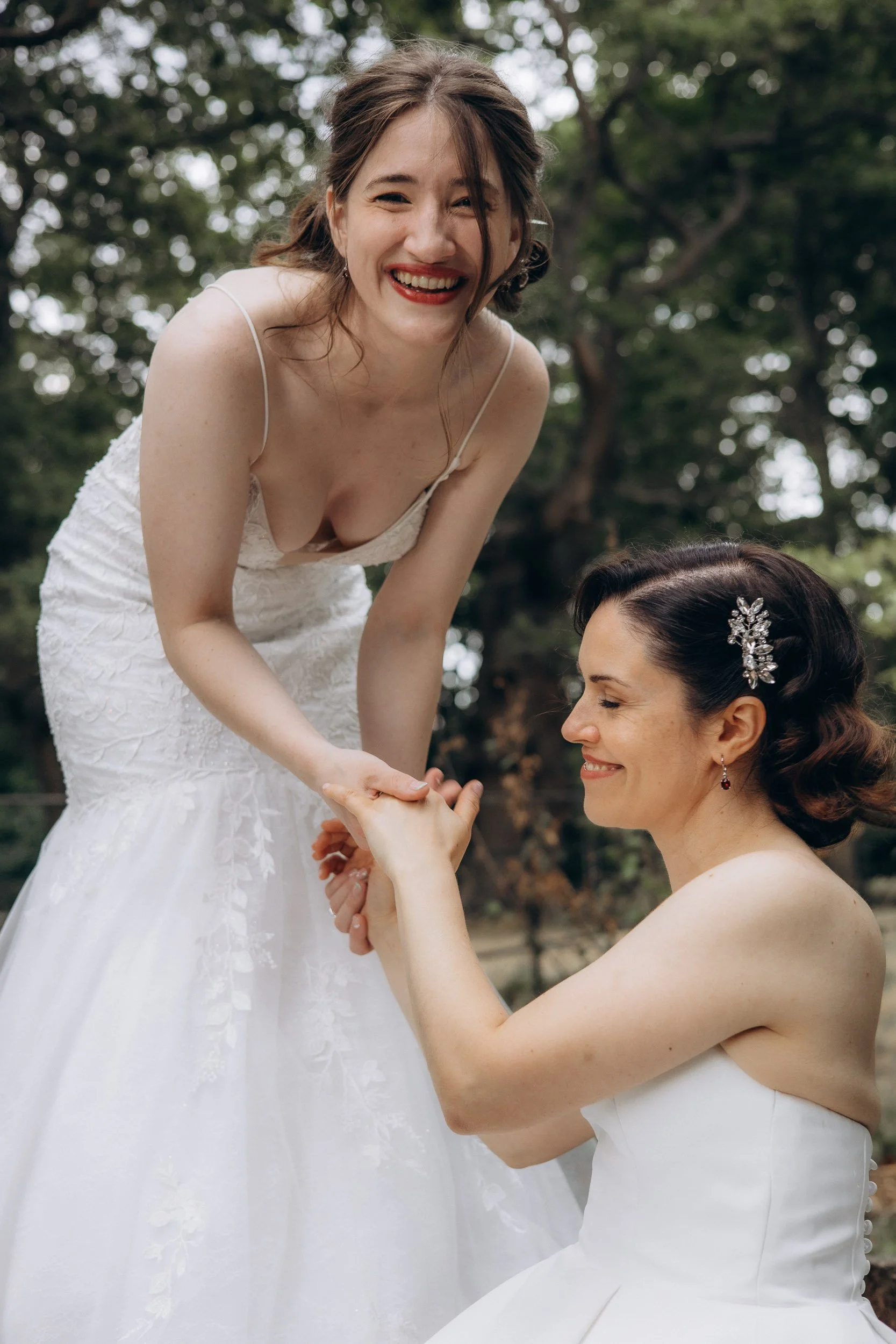  Two brides laughing and holding hands outside during their wedding — natural, unposed documentary wedding photography in London 