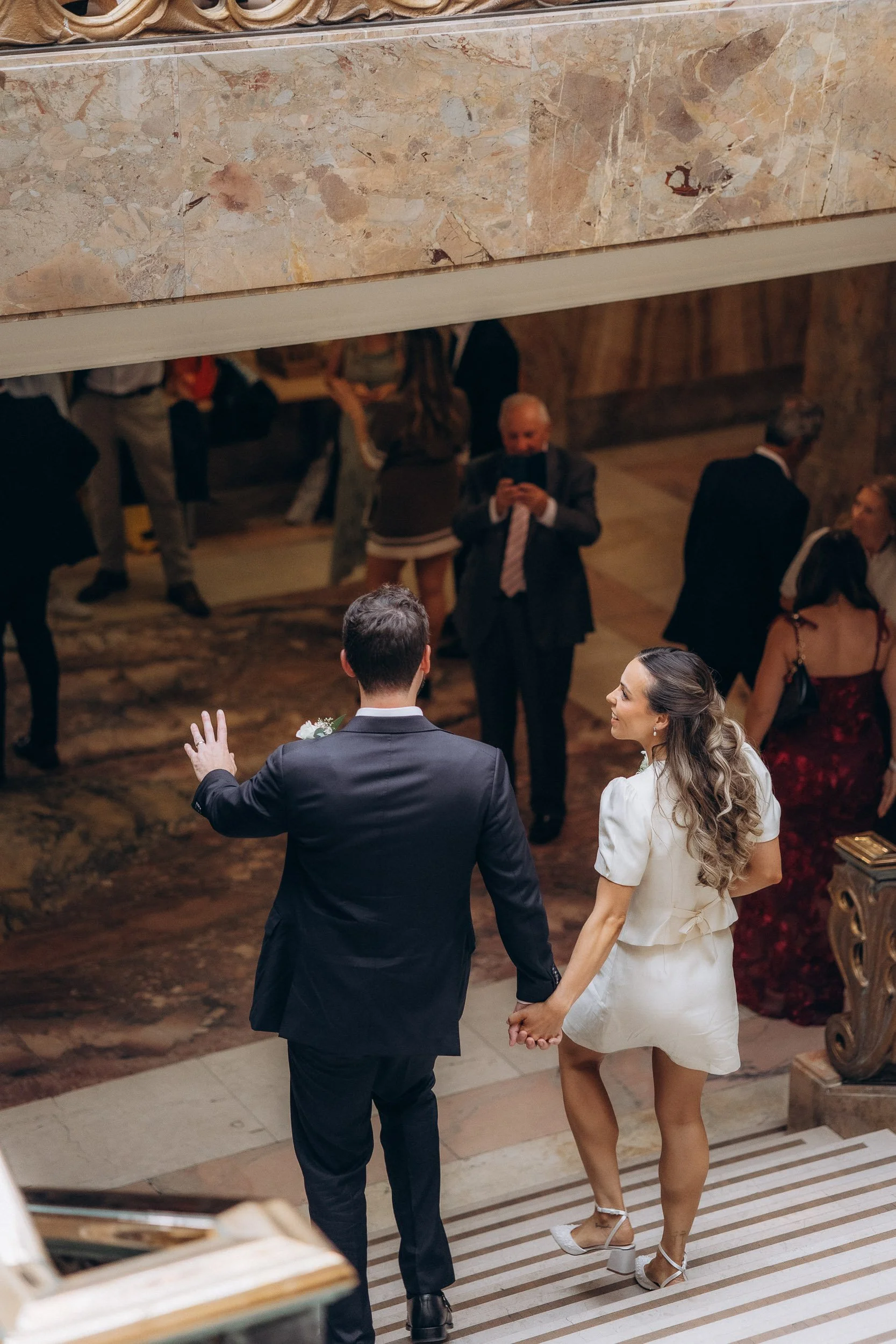  Newlyweds walking hand in hand down the marble staircase at Wandsworth Town Hall 