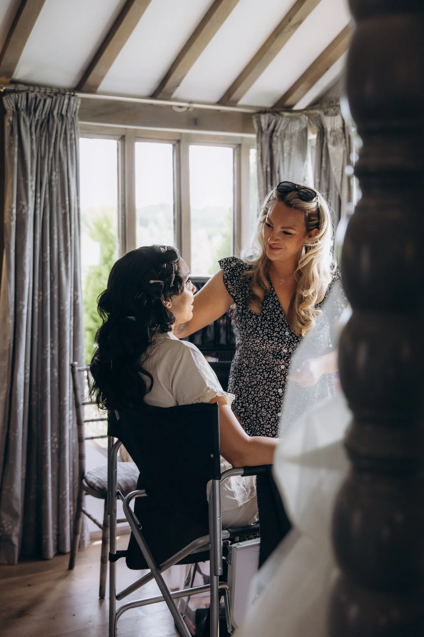 Bride having her hair styled by a hairdresser in natural window light