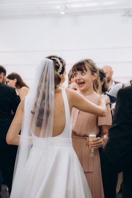 Bride in veil turning and smiling at the camera amid guests