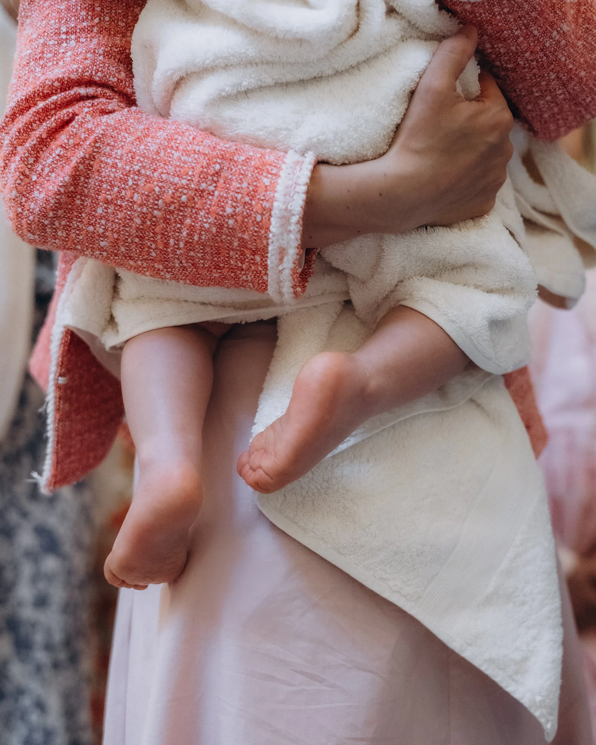 Baby's feet held during christening, candid documentary-style photography