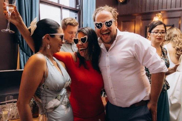 Group of guests wearing novelty sunglasses and laughing together