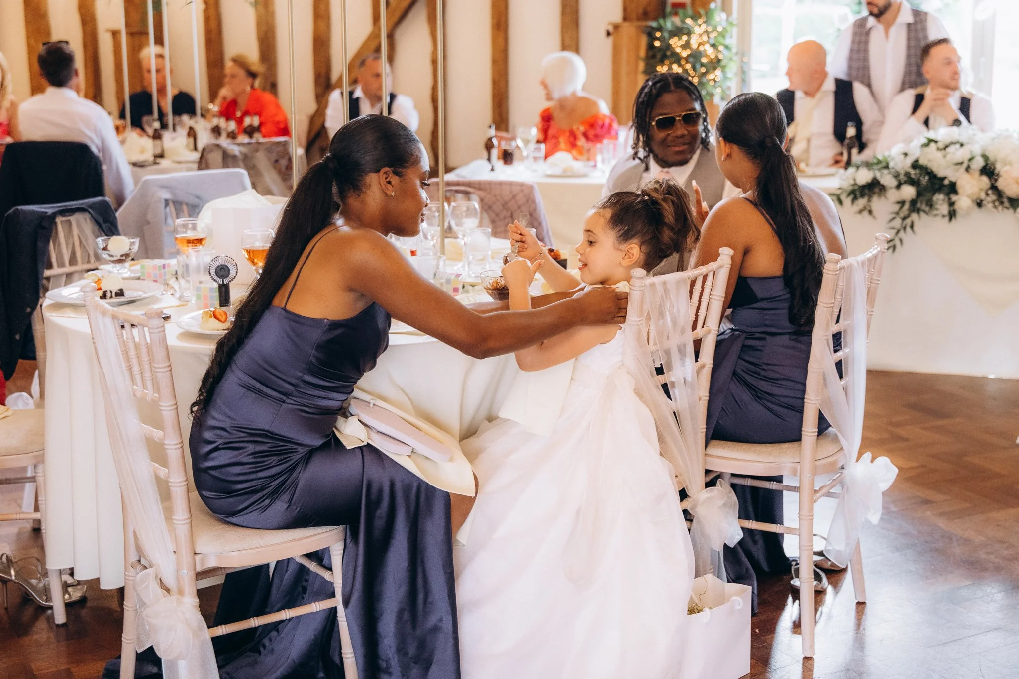 Bridesmaid adjusting the bride's earring at the reception table
