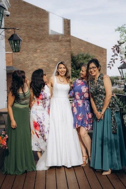  female guests posing together in a garden, wearing colourful floral dresses at The Old Ship pub