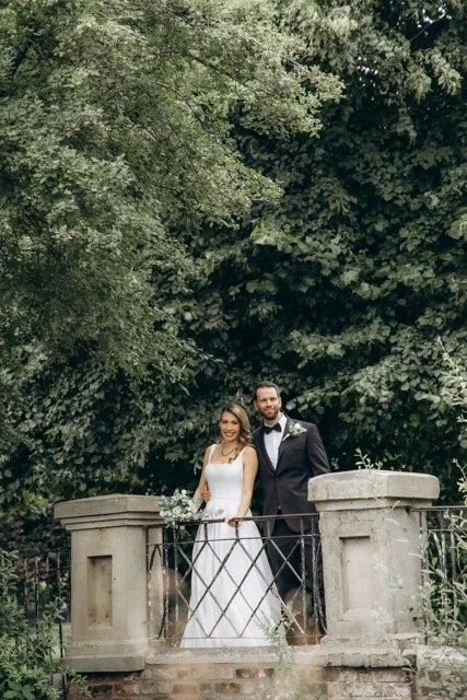 Bride and groom standing together on a stone balcony surrounded by lush greenery