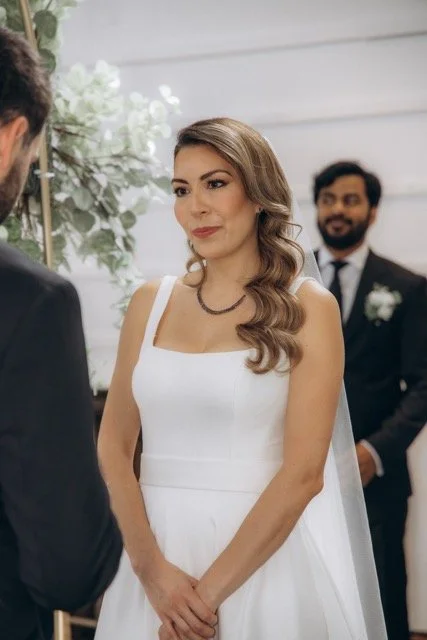 Close-up of the bride smiling during the ceremony, guests visible in the background