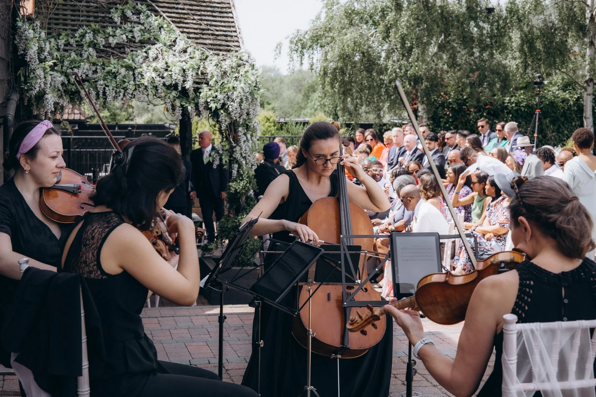 String quartet playing live music outdoors as wedding guests gather