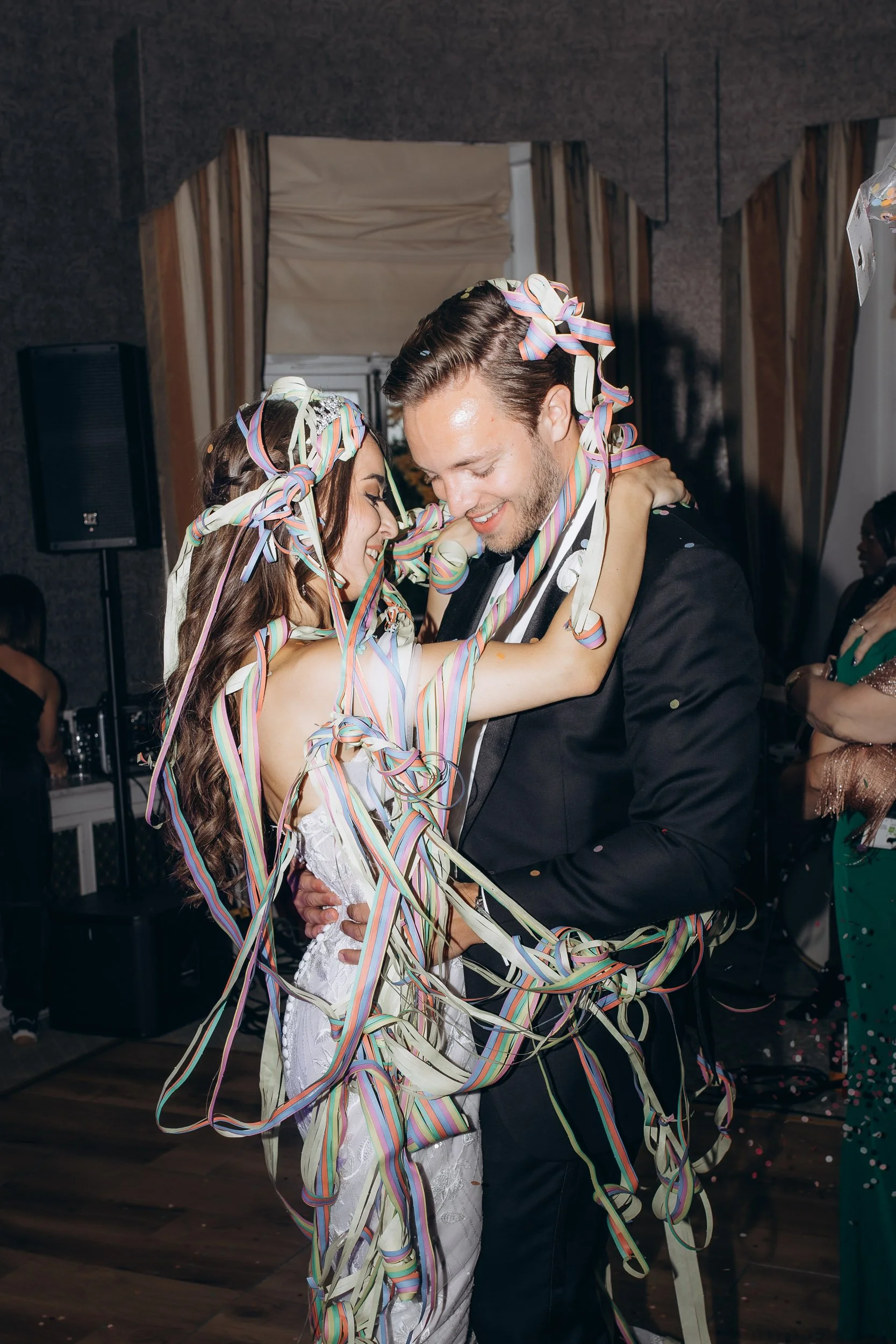 An authentic and high-energy photograph of a wedding couple's first dance with colorful streamers at a London reception.
