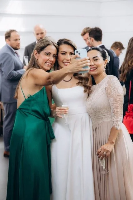 Bride taking a selfie with two guests, one in a green dress