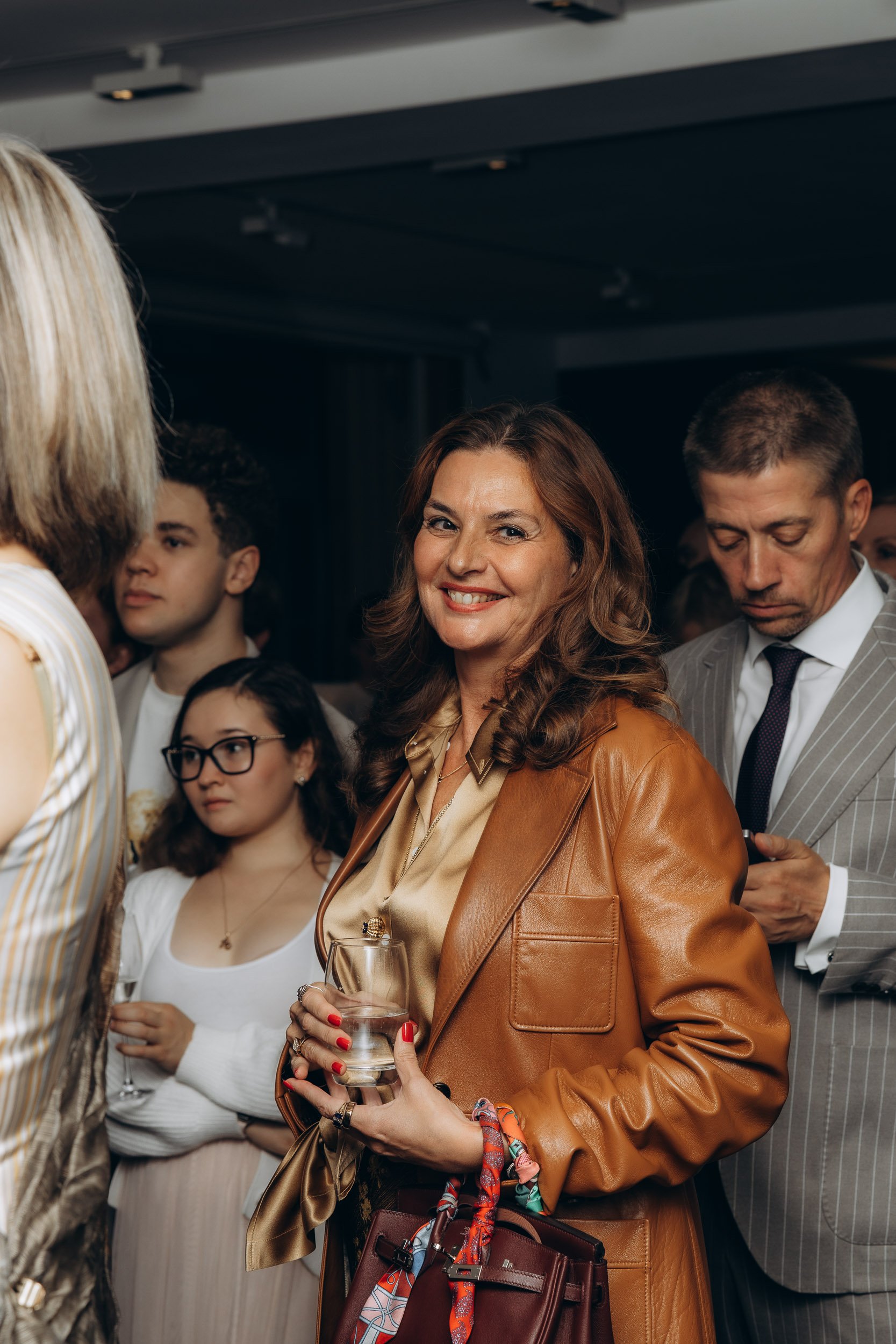 Guest in a leather jacket smiling with colleagues at a reception