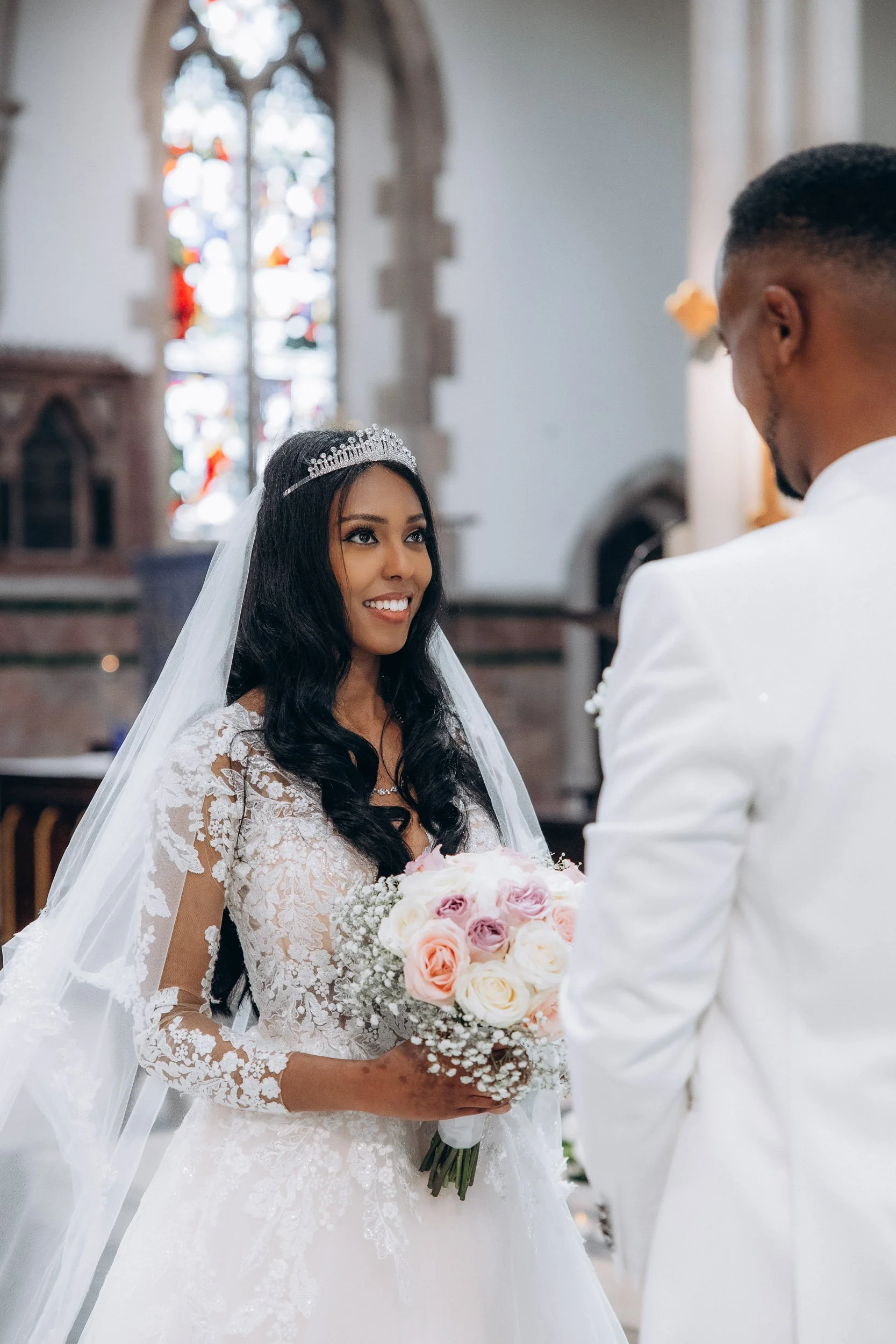 Close-up candid shot of a smiling bride looking at her groom during their wedding ceremony at [Church Name], London; capturing authentic emotion.