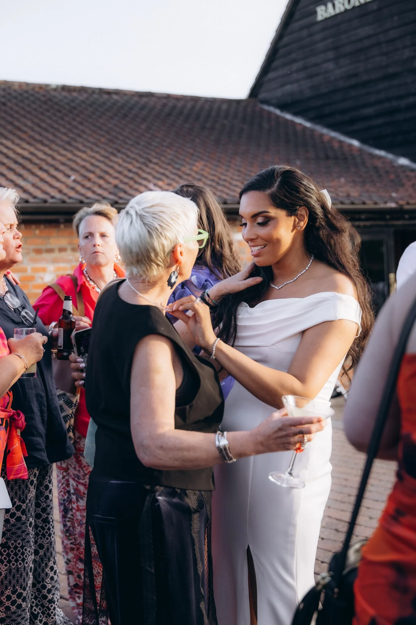 Bride adjusting another guest's corsage outdoors before the reception