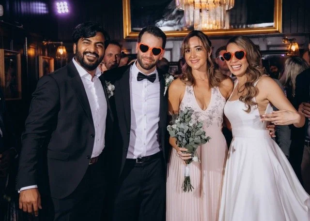 Bride, groom, and two friends posing together inside the venue, all smiling warmly